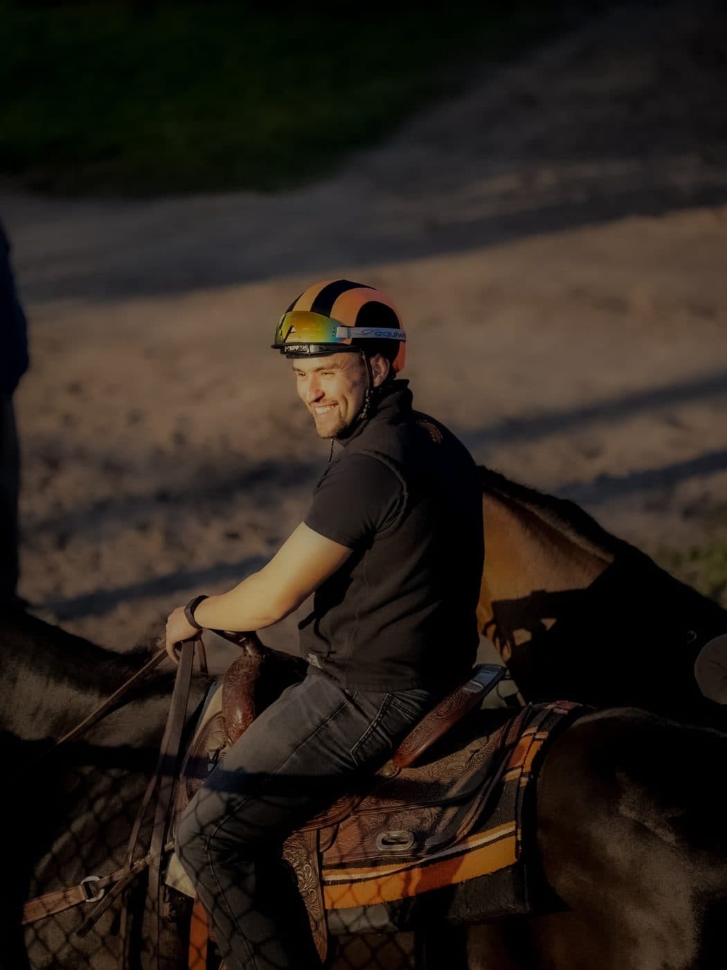An exercise rider taking a horse out on the training track before sunrise
